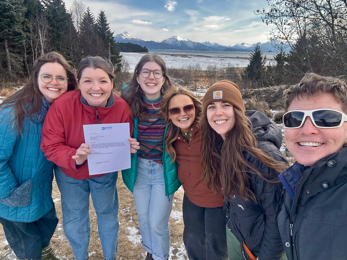 Volunteers pose with their chapter charter in front of a snowy mountain background