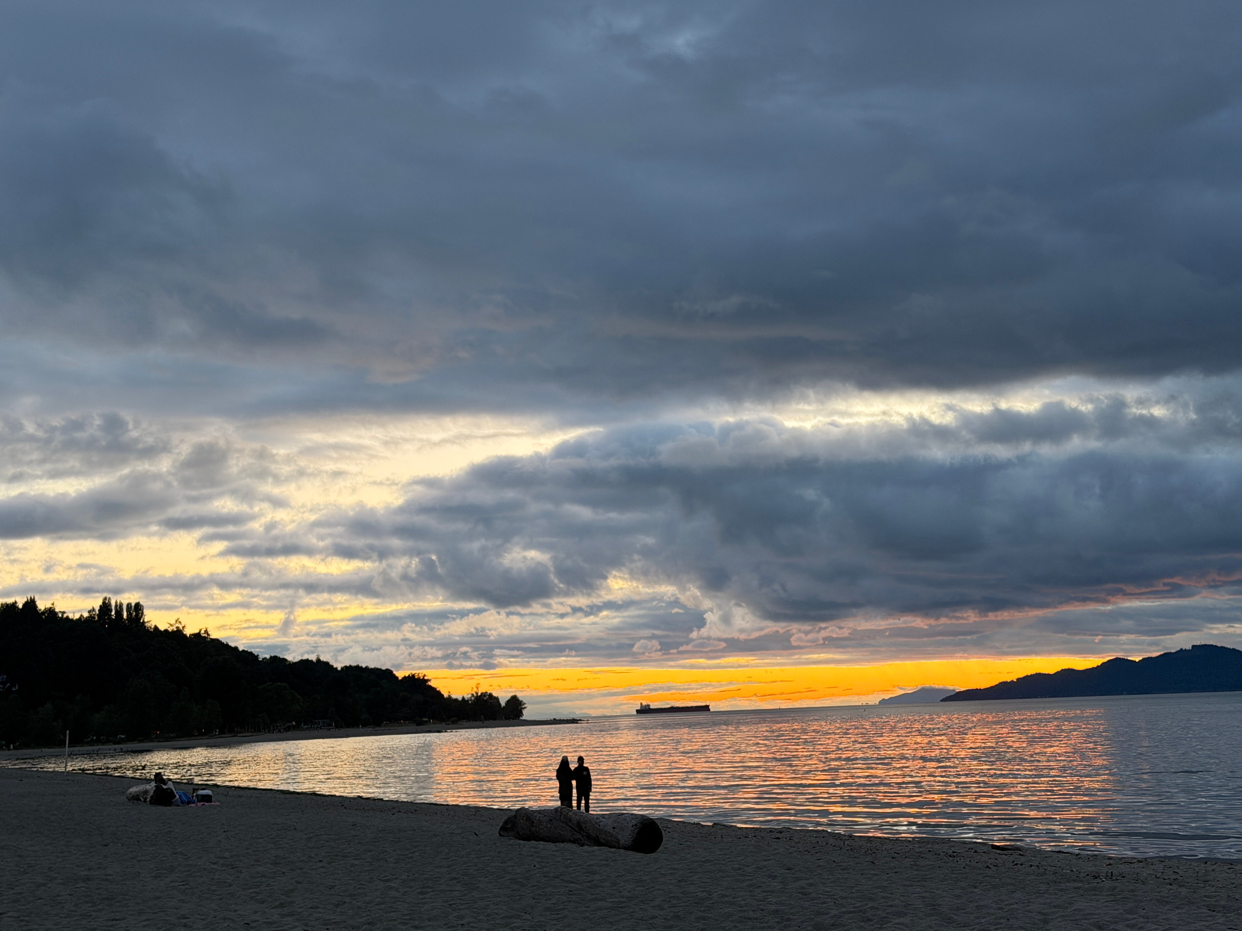 Silhouette of two people standing on a sunset beach
