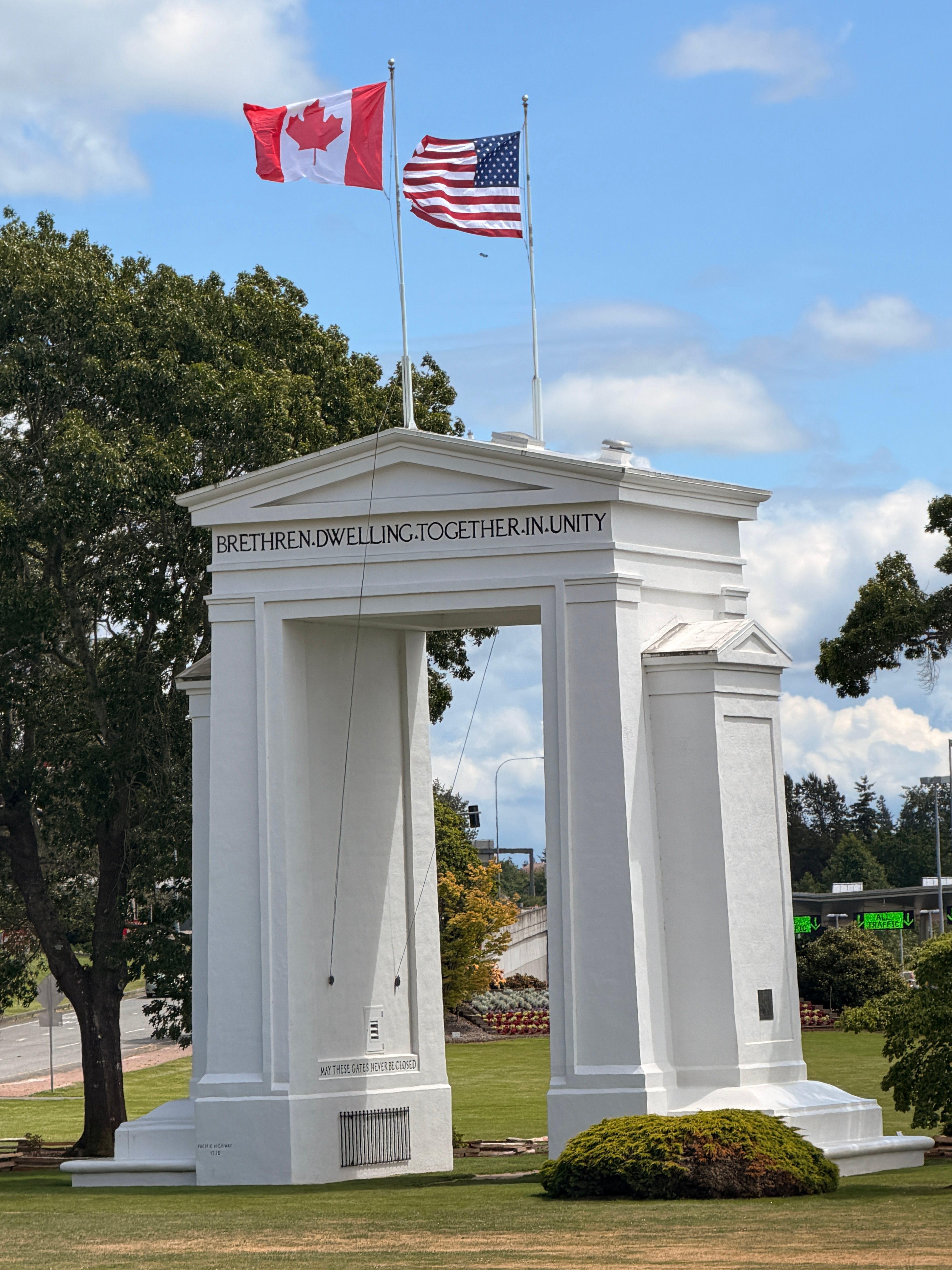 Canada and US flags waving above the white Peace Arch