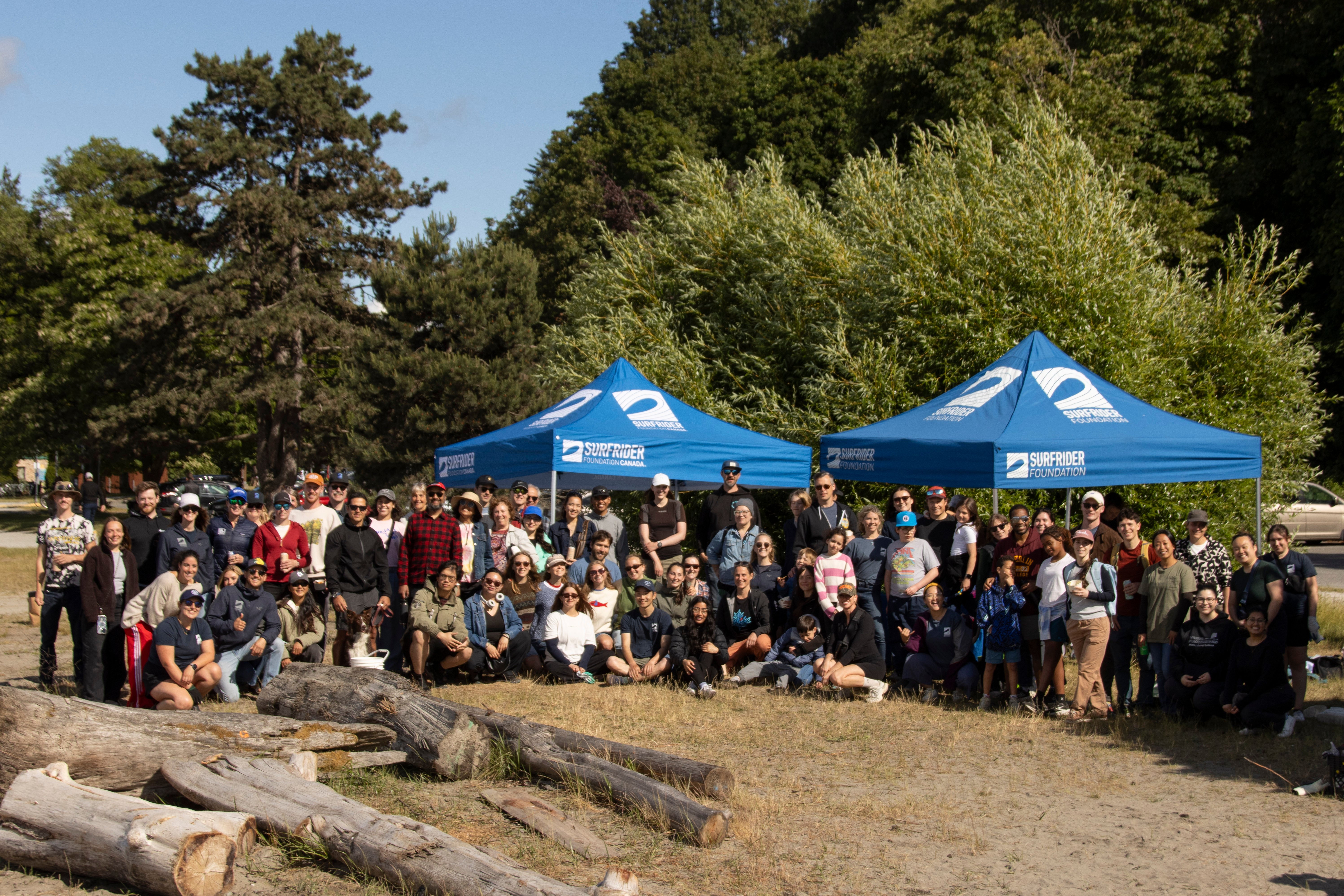 Dozens of volunteers posing in front of Surfrider Canopies after a beach cleanup