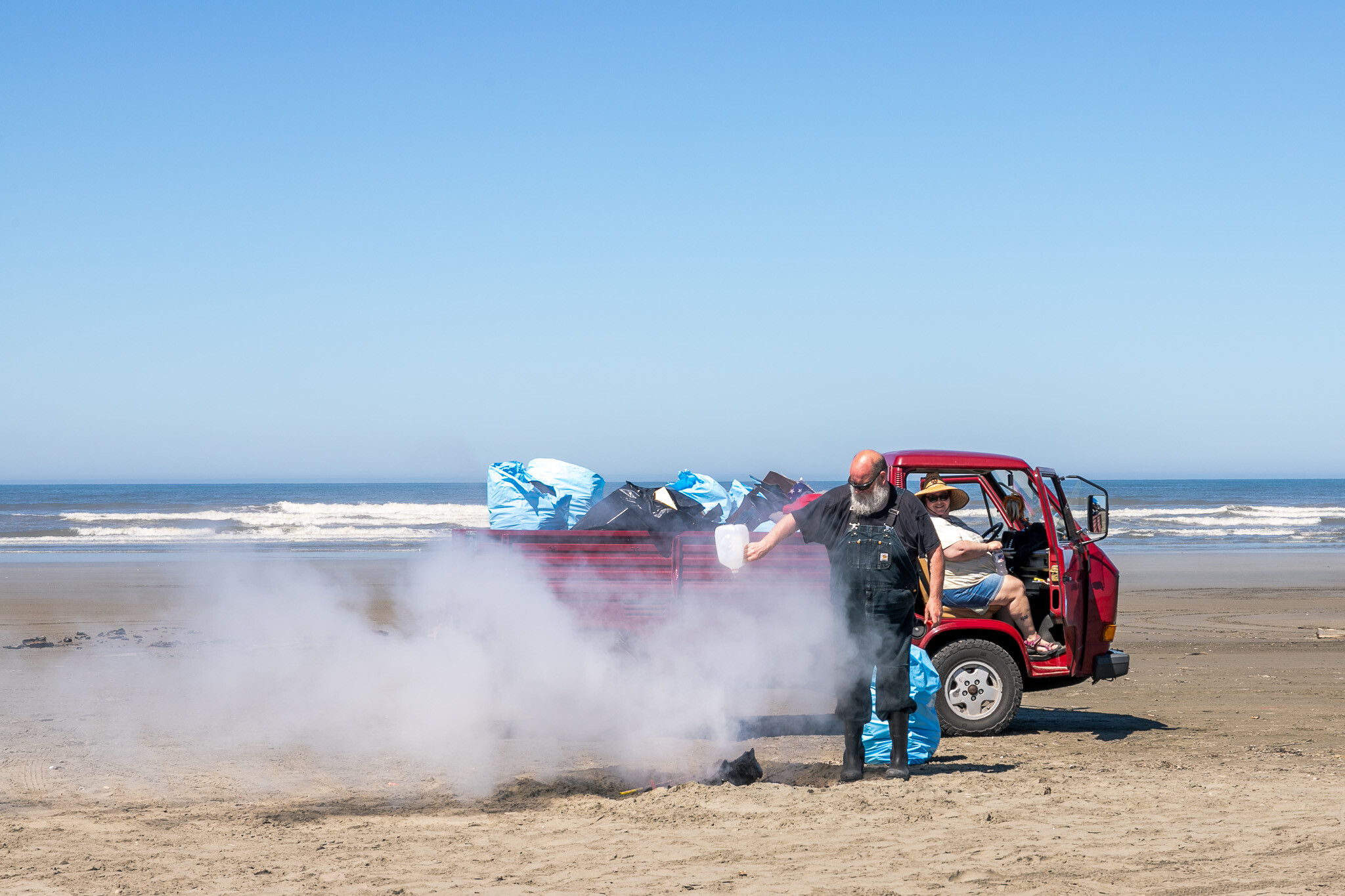 Volunteers putting out a trash fire on the beach