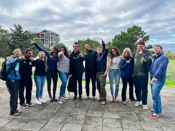 Surfrider staff at the 2023 Cascadia Conference posed outside under a textured gray cloudy sky with dunes in the background 