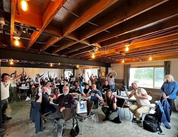 Conference attendees in the presentation hall holding up their reusable mugs and water bottles