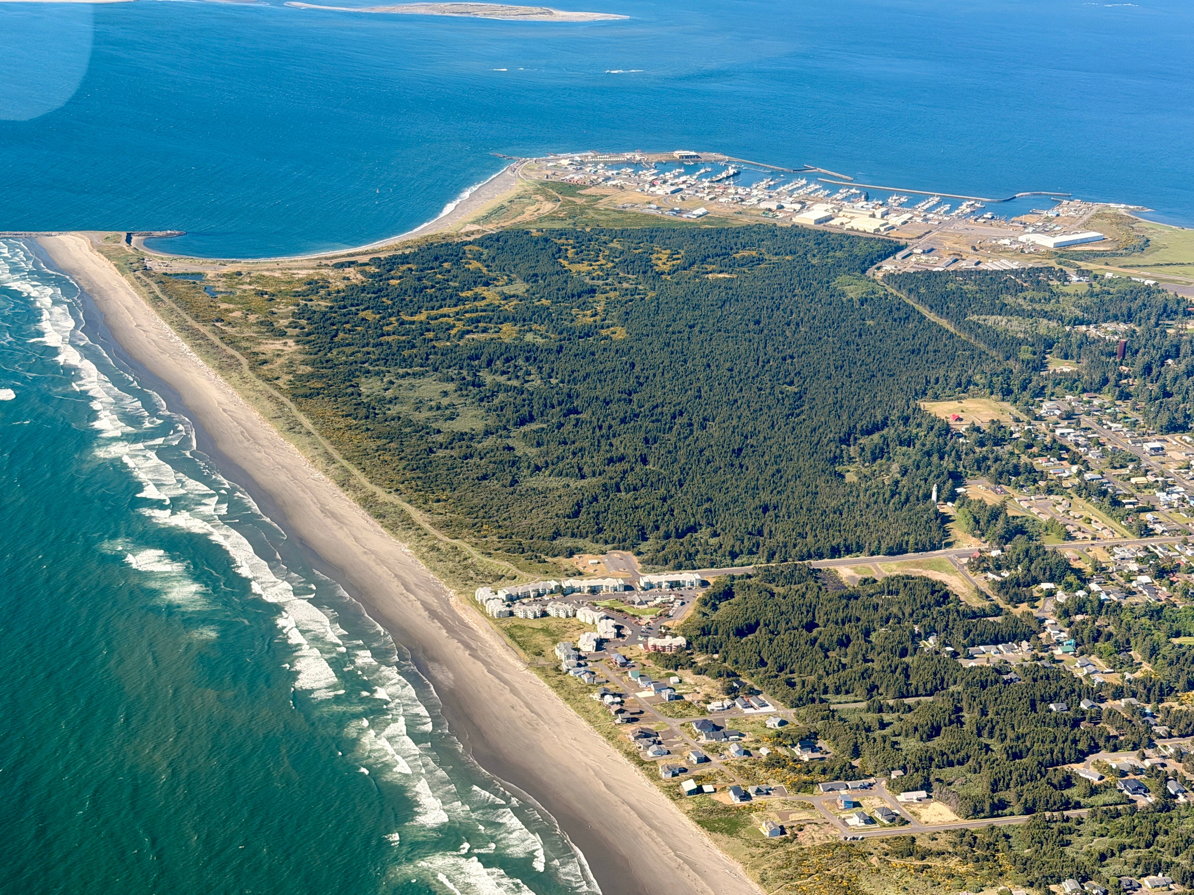 An aerial shot of Westport state Park surrounded by bright blue water; Photo credit: Liz Schotman and Lighthawk