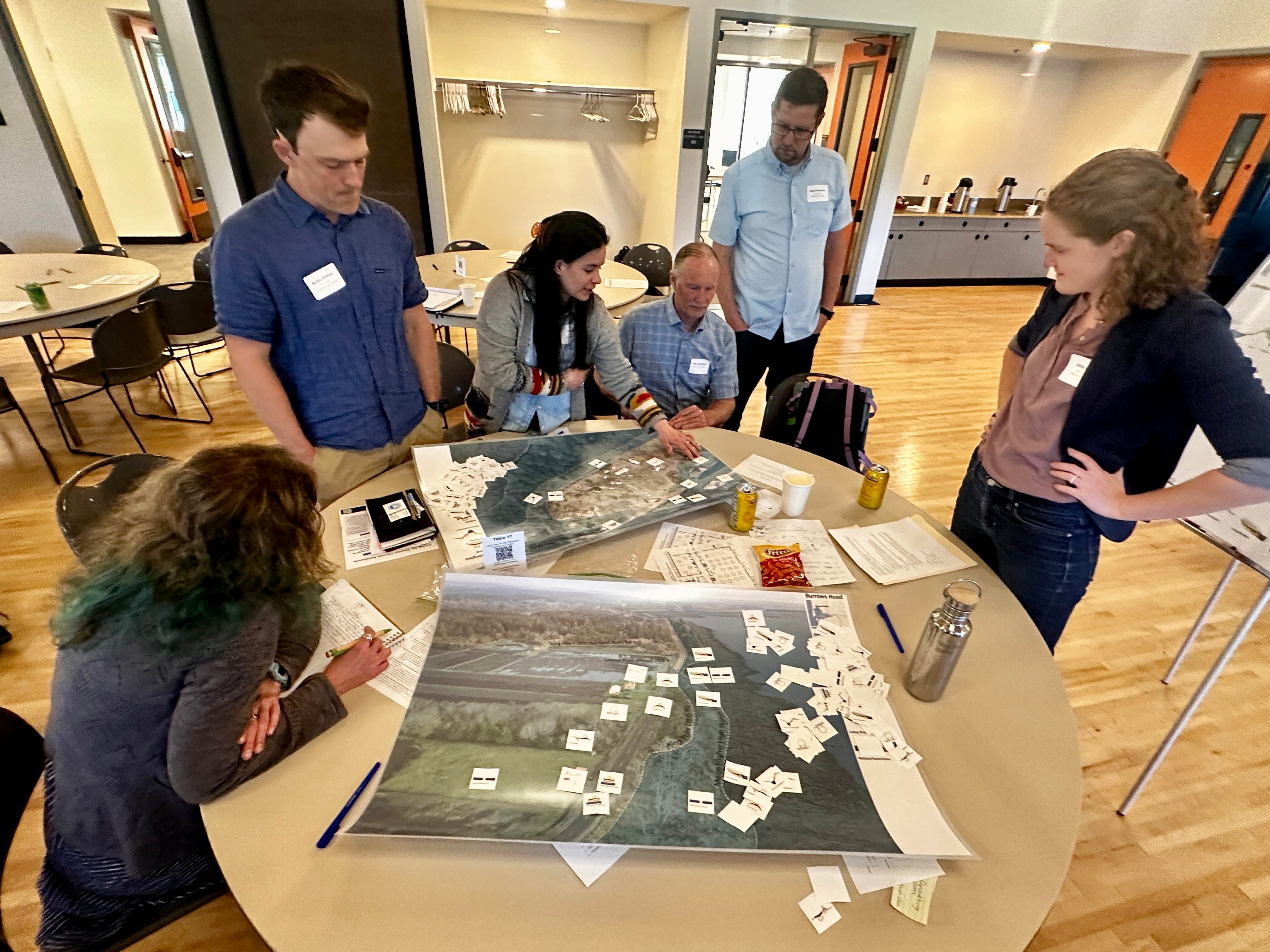 Several people gathered around a table with a map and tiles to place on it as part of a CHRN exercise in coastal planning and adaptation