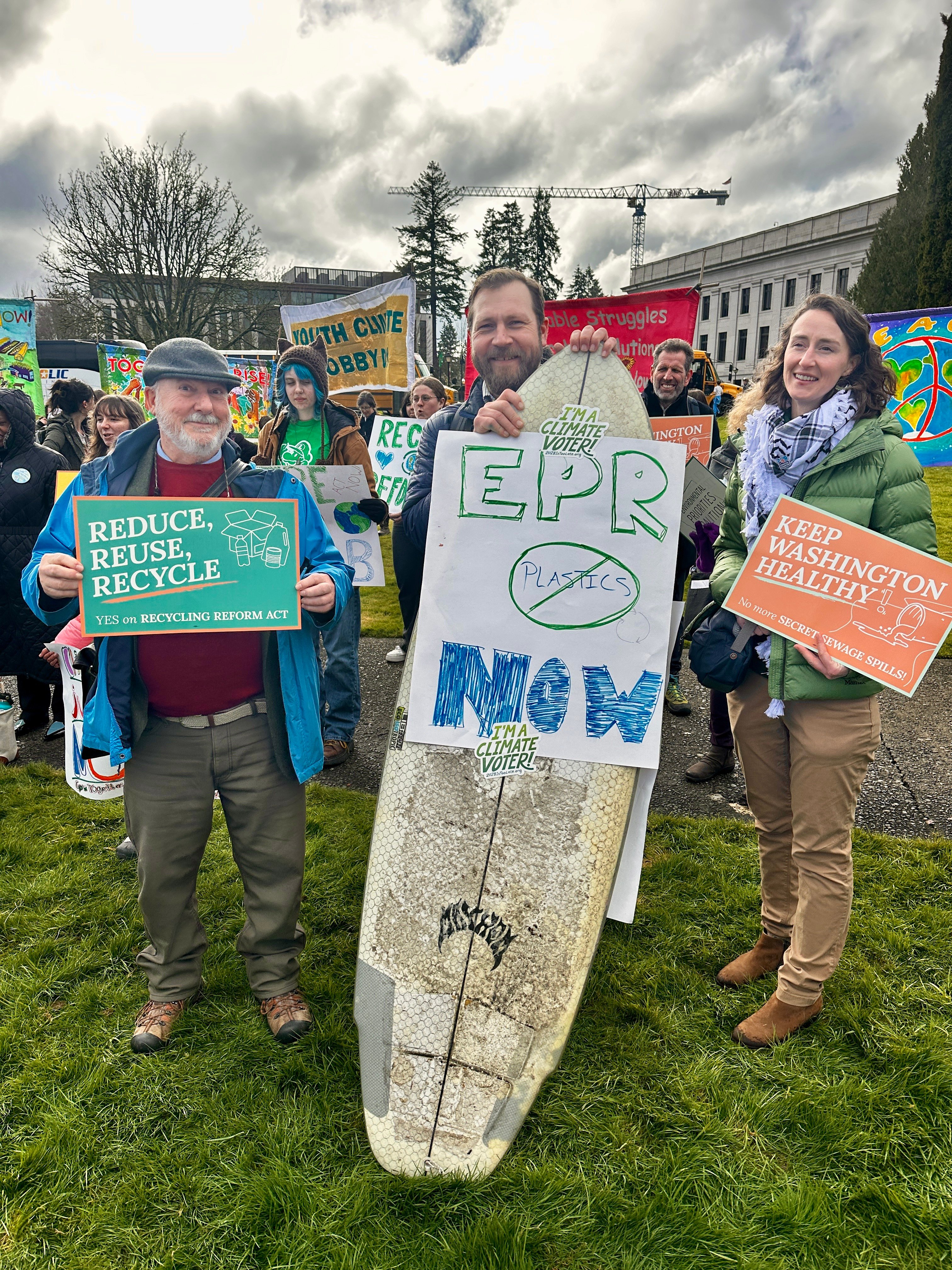 WA Staff and volunteers pose in front of the capital with signs and a surfboard that state EPR Now