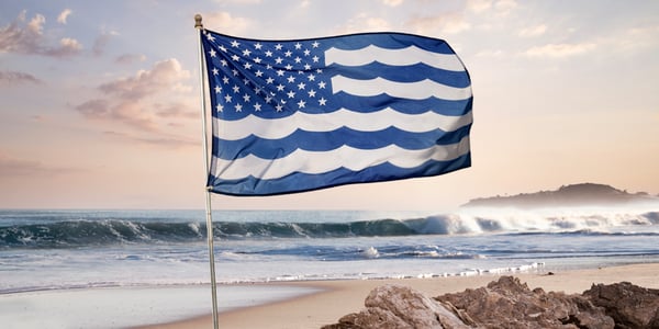 A United State and Oceans of American flag waving over a beach