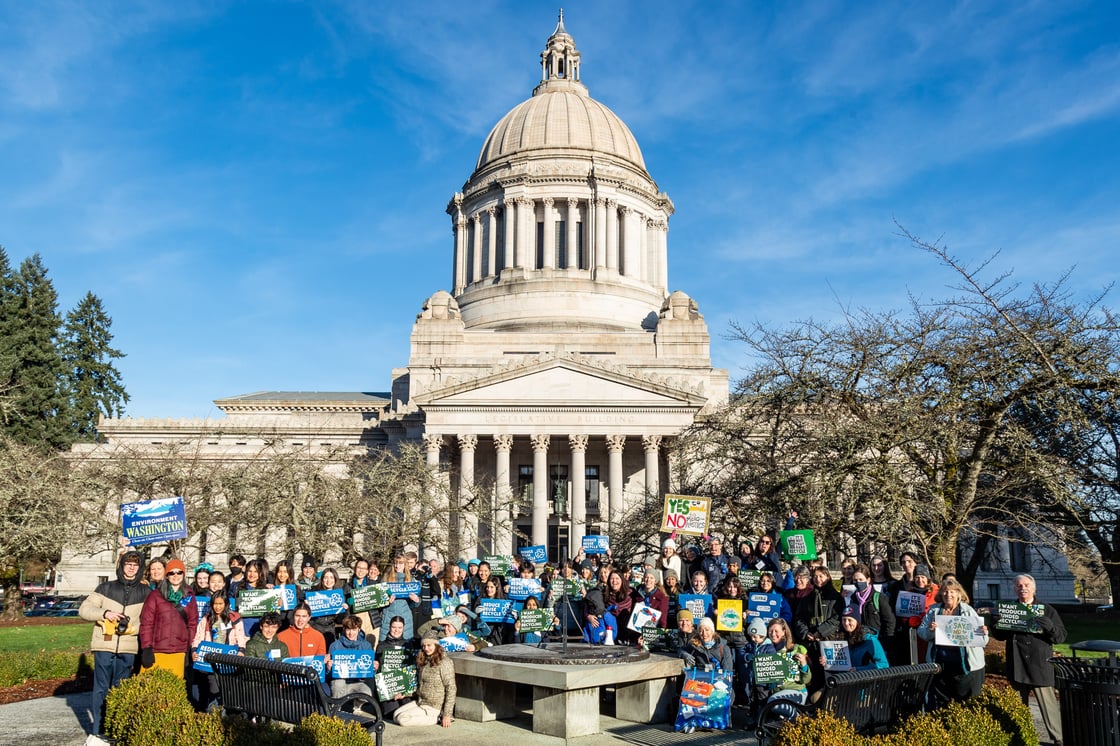 Dozens of volunteers in front of Olympia's Capitol Building holding up signs